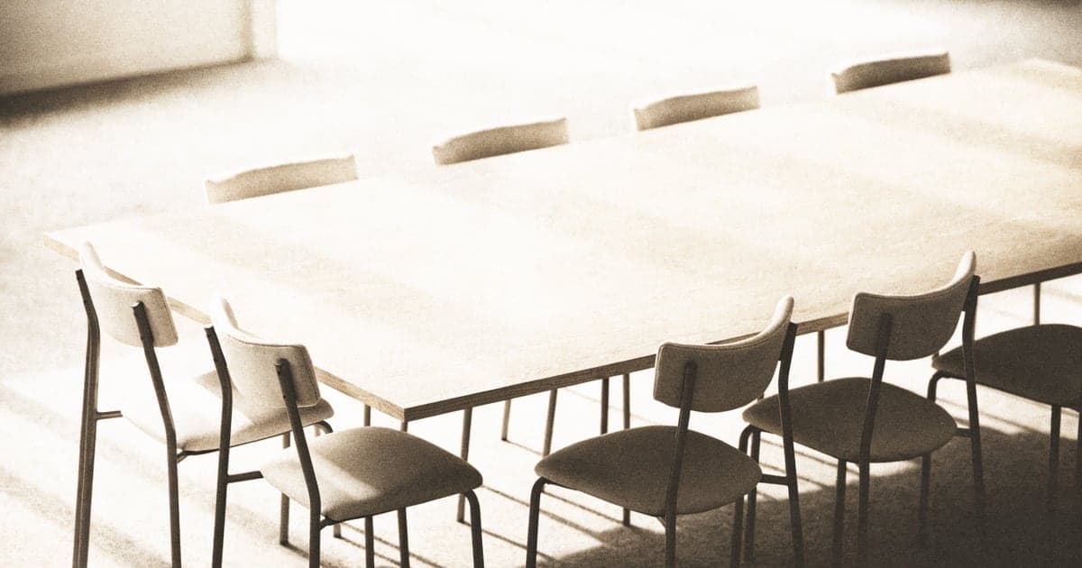 An empty boardroom table with chairs arranged evenly around it
