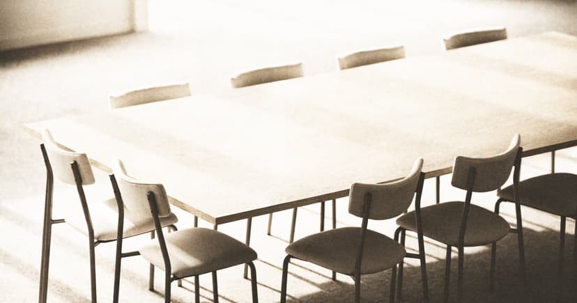 An empty boardroom table with chairs arranged evenly around it