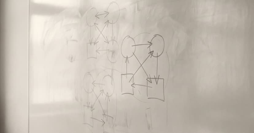 A wall-mounted writing surface carrying three overlapping diagrams, two of them partly erased